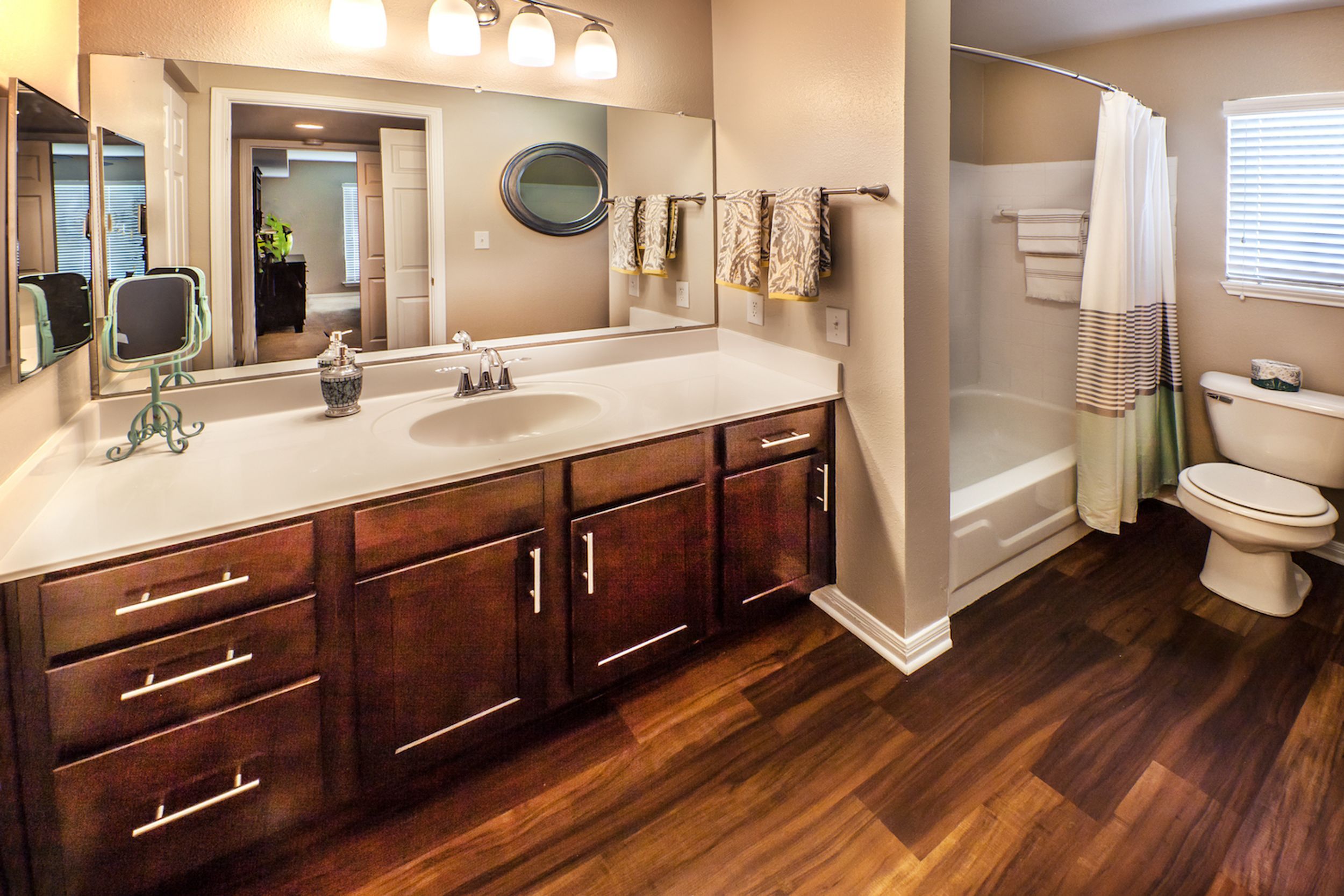 Bathroom with earth tones, hard wood laminate flooring, and dark wood vanity