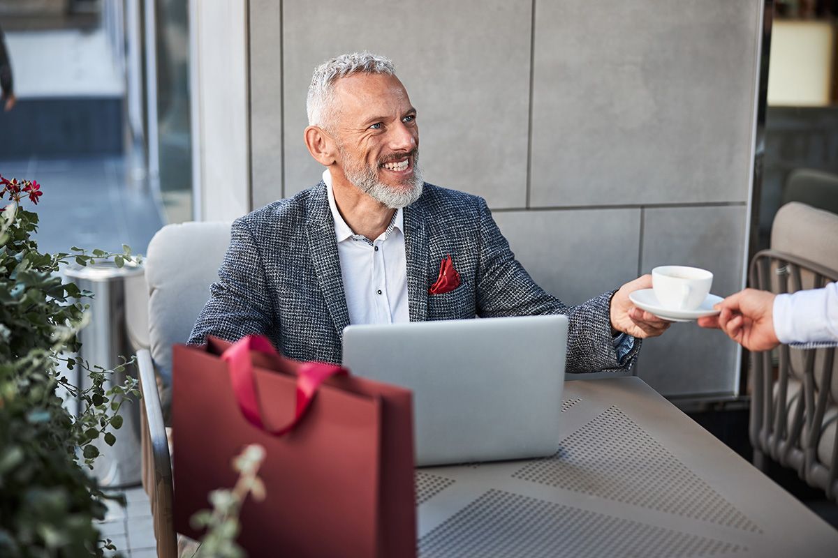 Man getting coffee with laptop